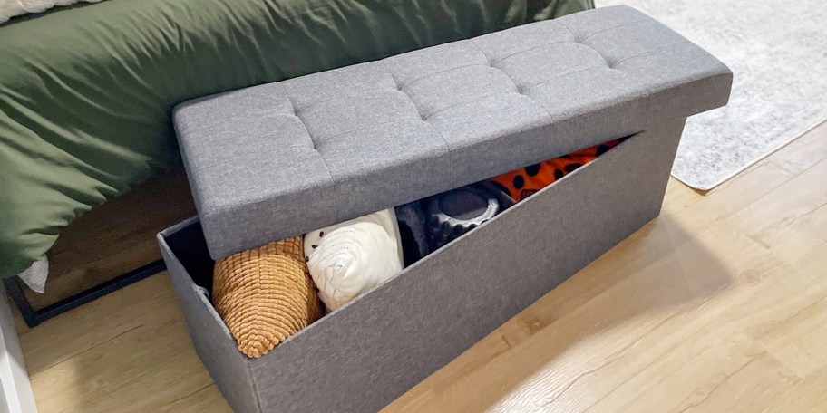 gray storage bench full of blankets 