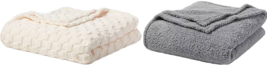 Two folded blankets sit side by side. The left is cream-colored with a textured pattern, and the right is gray with a soft, fluffy appearance.