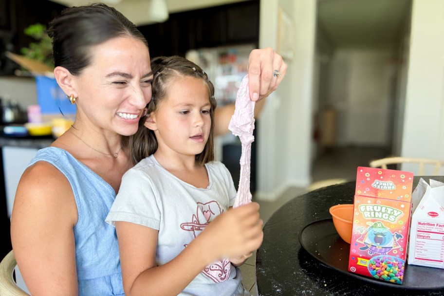 daughter sitting on mom's lap holding cereal slime