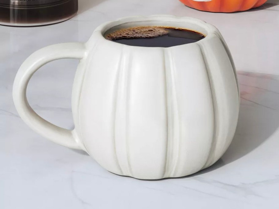 white pumpkin mug on table full of coffee 