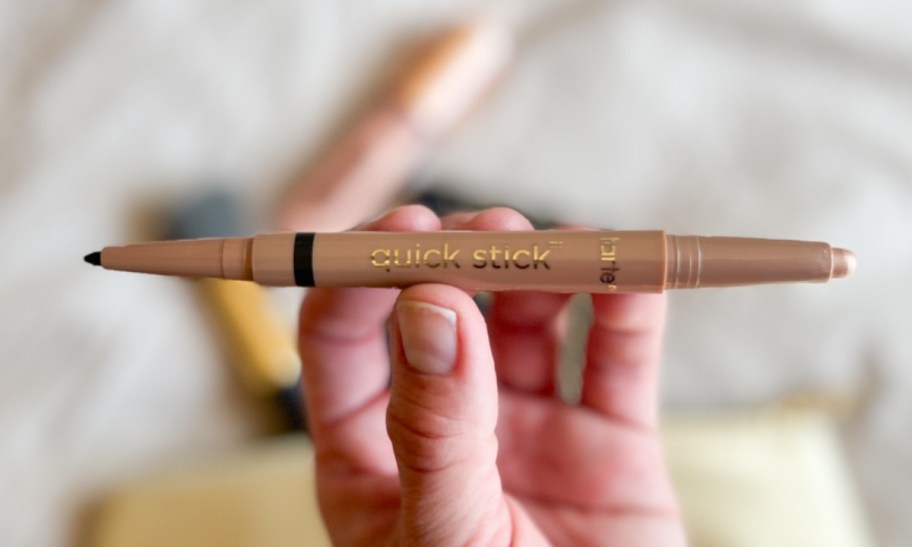 a womans hand holding an eye pencil