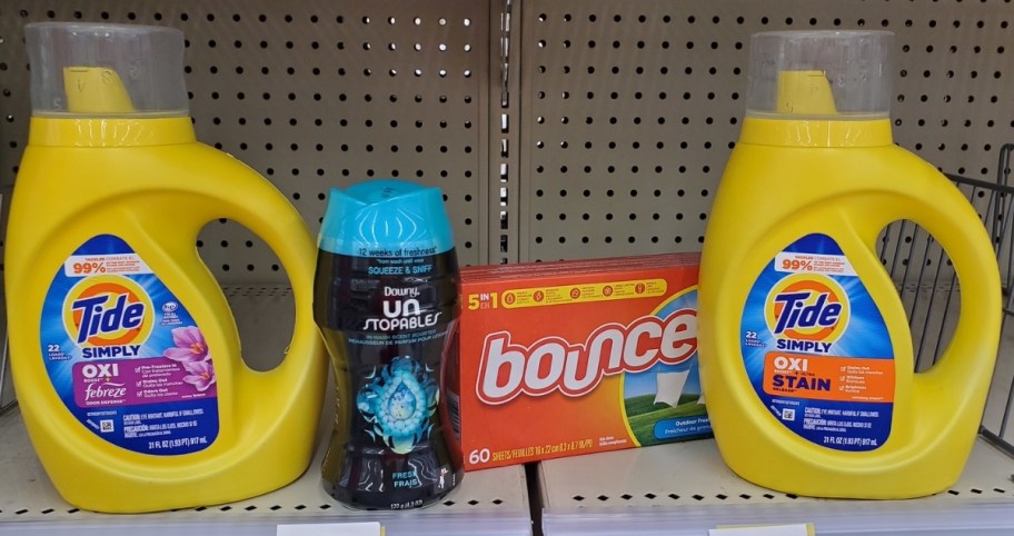 two bottles of tide, bounce dryer sheets, and downy scent beads on a store shelf