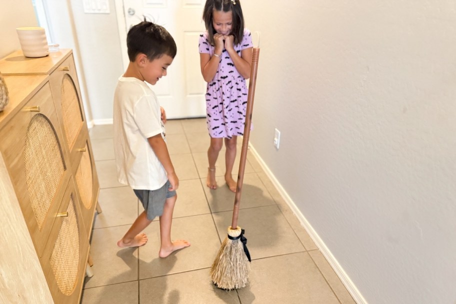 two kids playing with the floating broom
