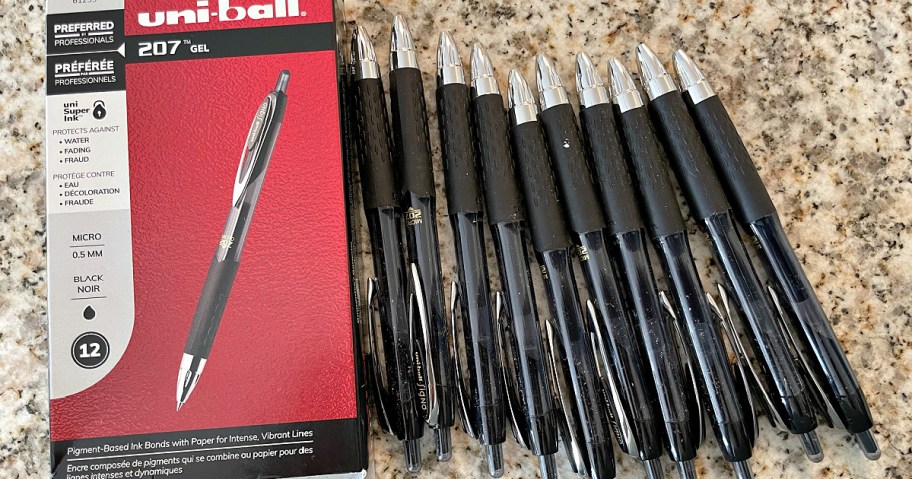 A box of uni-ball 207 gel pens is open on a speckled countertop. Beside it are 12 black gel pens neatly lined up.