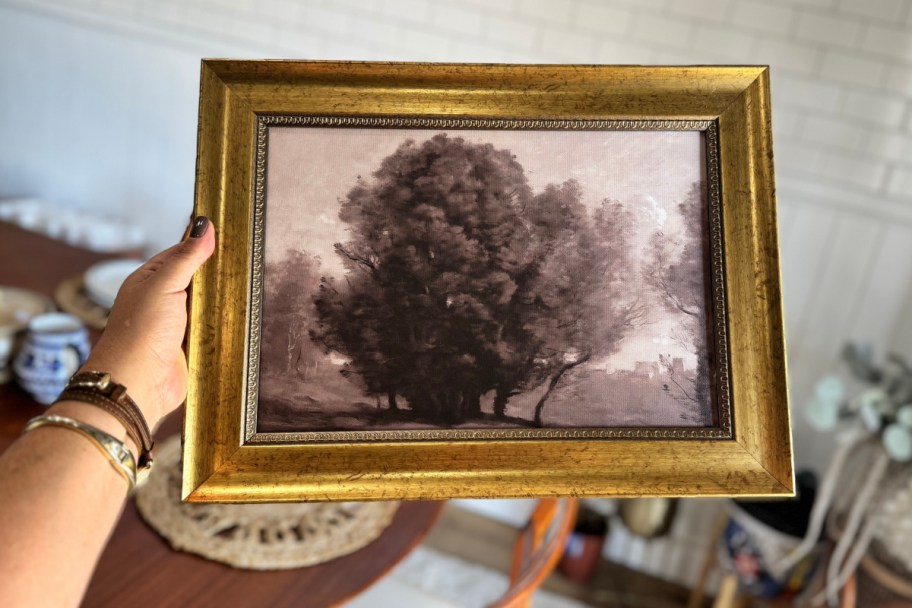 hand holding brown tree in gold frame