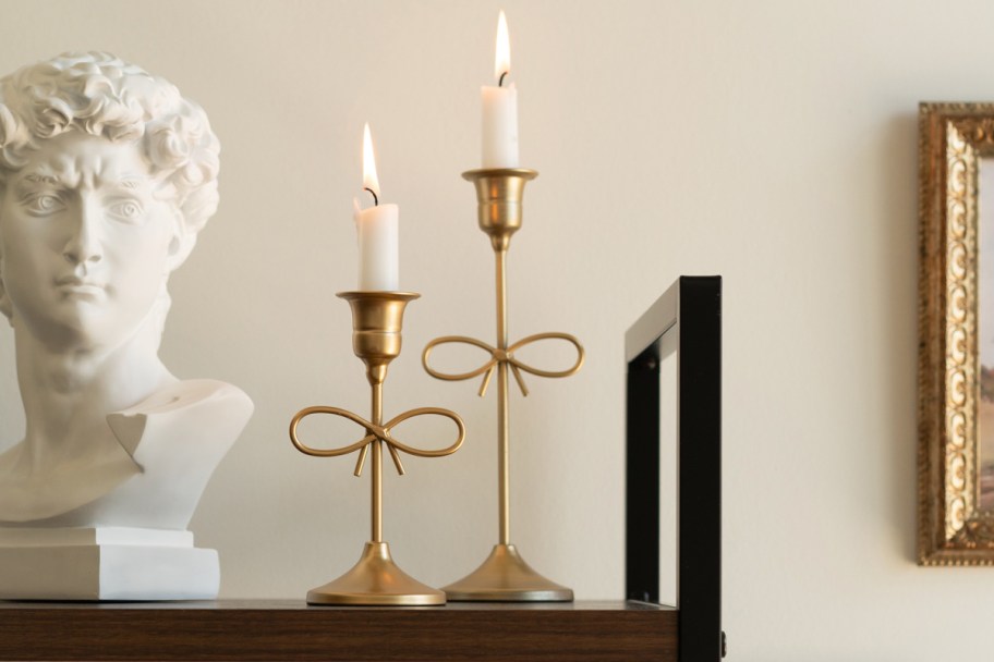 two gold taper candle holders with bow
