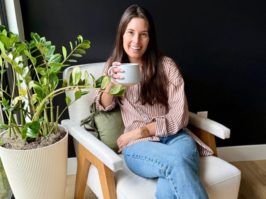 woman holding coffee mug sitting on white chair