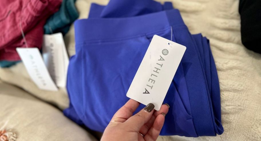 hand holding the tag of a pair of athleta pants