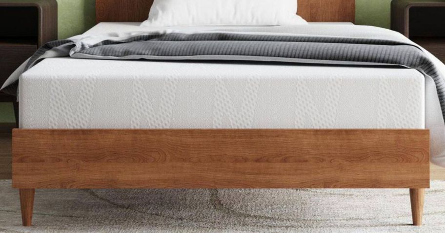 A wooden bed frame with a bed revealing an exposed mattress in a bedroom