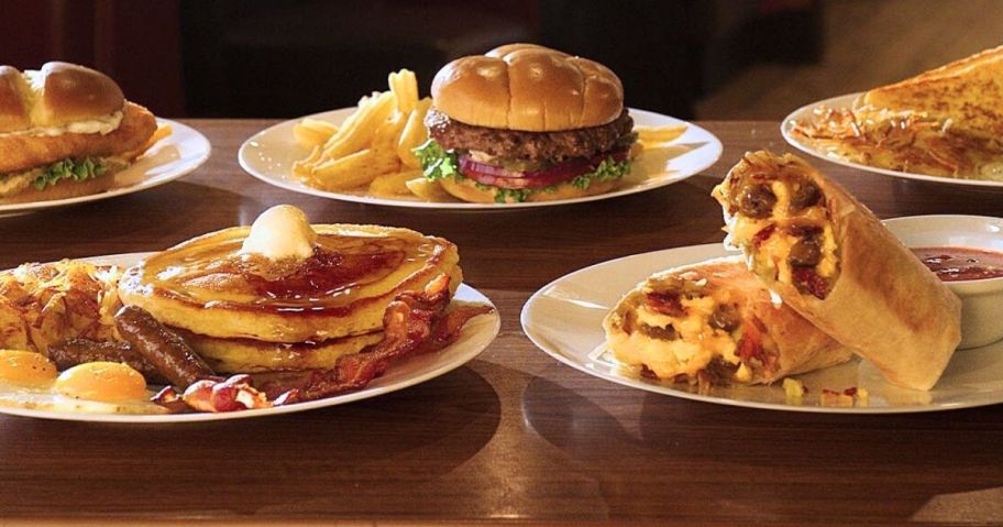 Several Plates of meals on a table including burgers, pancakes, and more