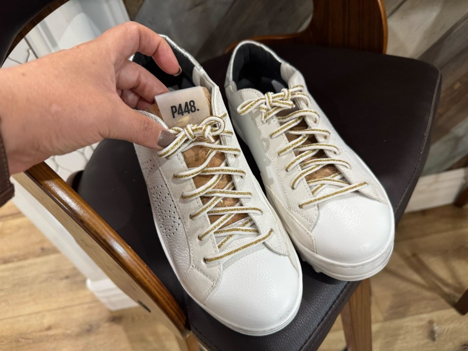 woman holding white sneakers in her hands