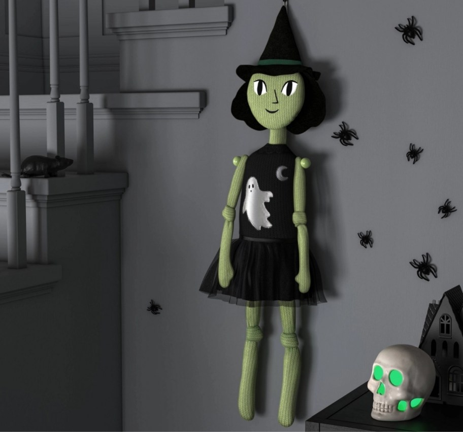 a green nit halloween witch hanging on a wall by a staircase