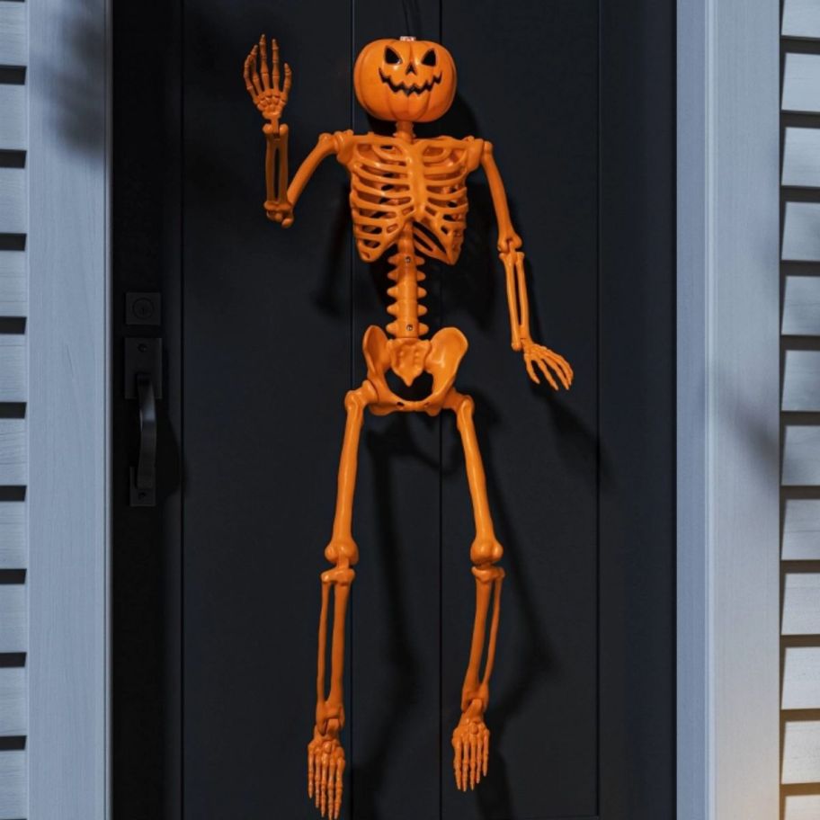 pumpkin head skeleon displayed on a black wall
