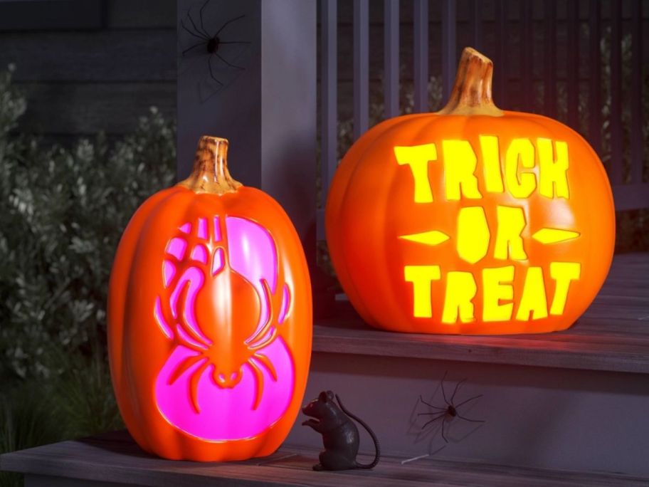 two pumpkins displayed on the porch with halloween carvings 