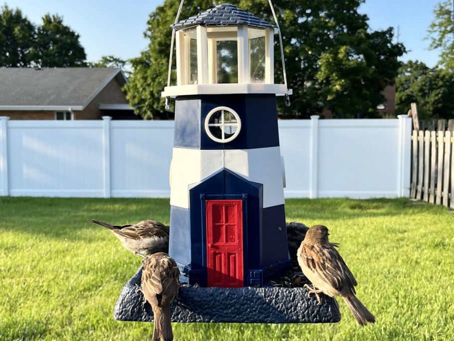 navy blue and white striped lighthouse bird feeder with birds on it