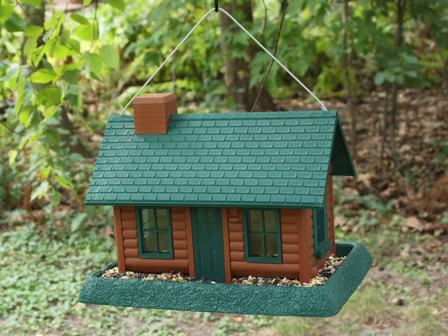 green and brown log cabin style bird feeder