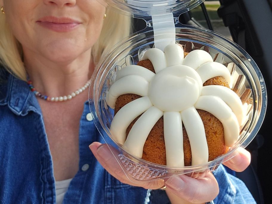 A woman holding a small cake with white icing