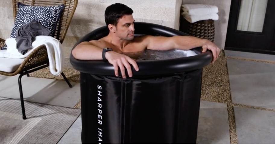 man sitting in sharper image portable ice bath tub outside