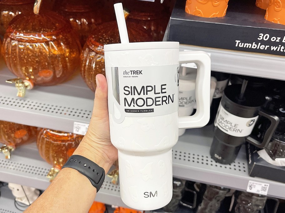 hand holding up a white ghost print tumbler in store