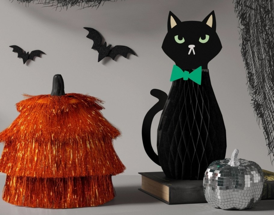 an orange fringed pumpkin shown with honeycomb paper black cat and a disco ball pumpkin