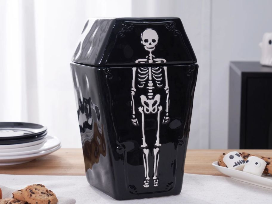 black coffin-shaped treat jar with skeleton on it on table