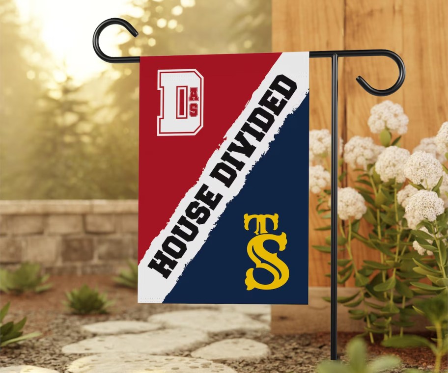 house divided sports flag with red and blue yellow teams in mulch bed outside