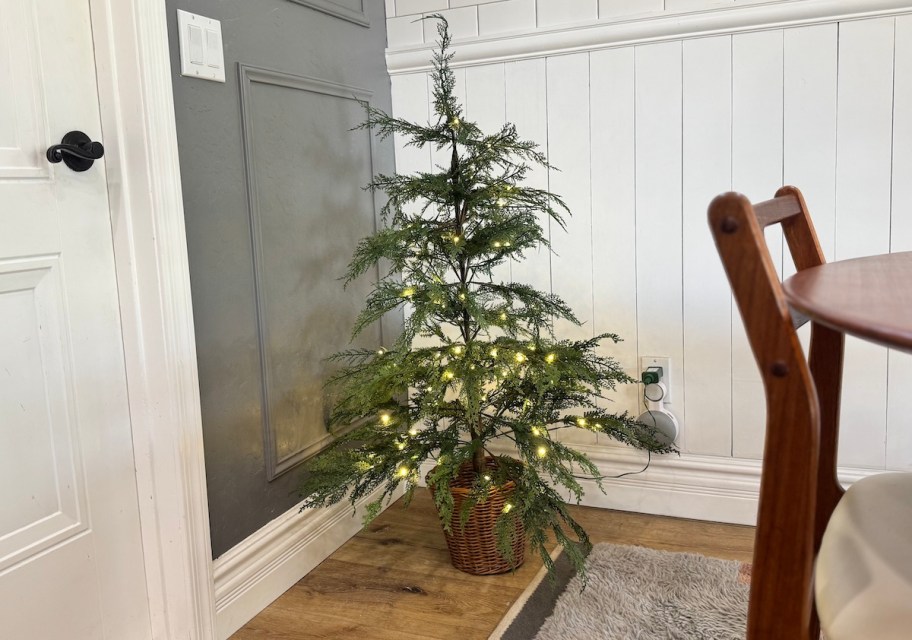 small prelit christmas tree on floor in corner of dining room