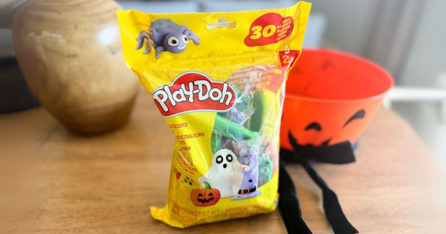 Play-Doh Halloween Pack on table next to black bow and orange pumpkin bowl