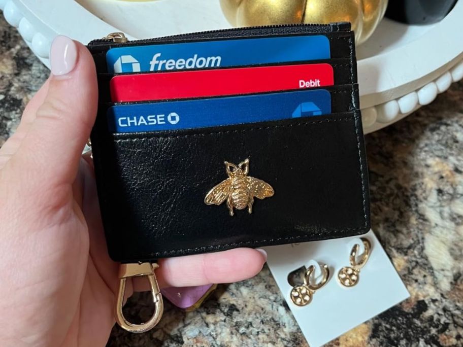hand holding a small wallet with bumble bee on it 