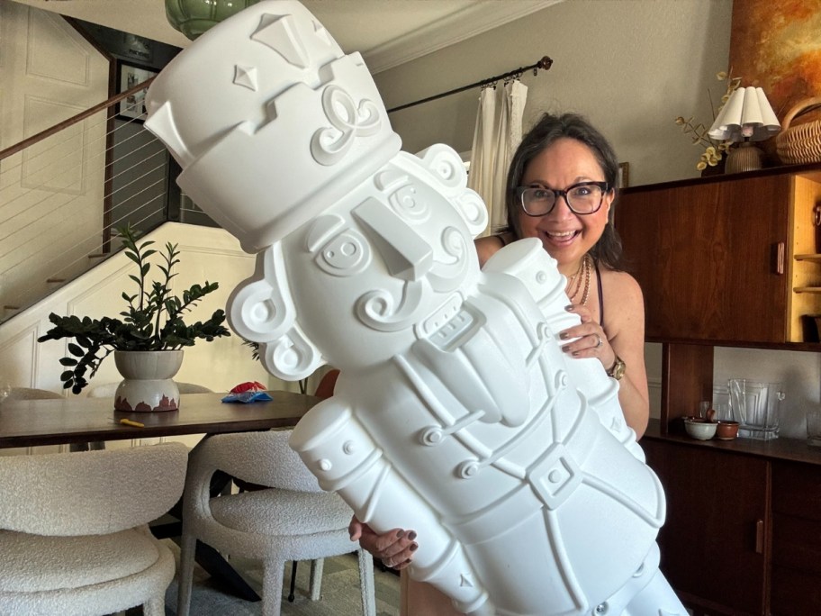 woman holding a large plastic Christmas Nutcracker figure