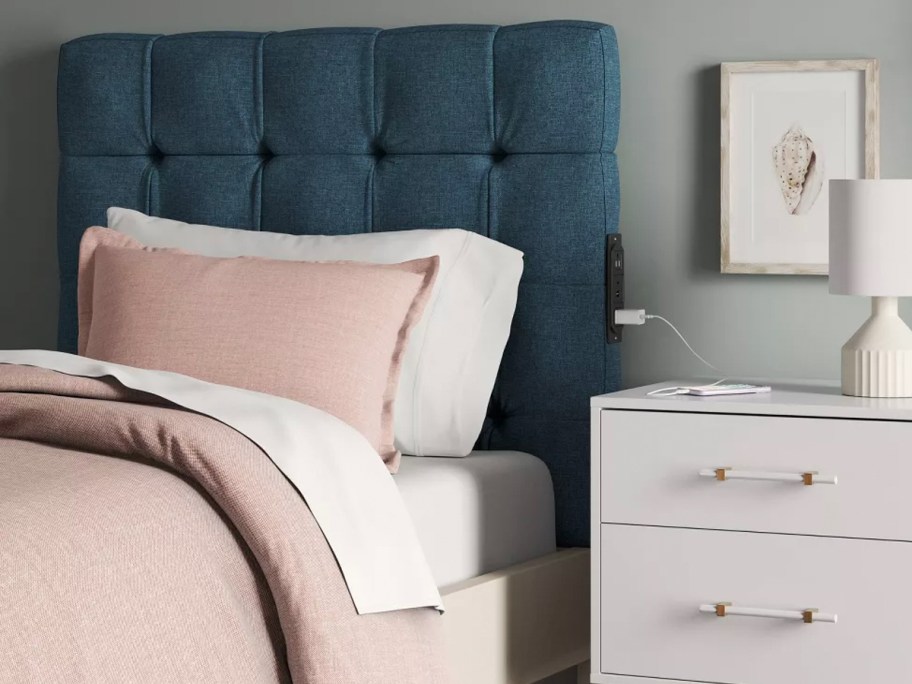 blue headboard above bed wit pink and white bedding 