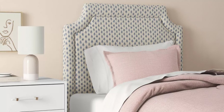 blue and white printed headboard hanging above bed with pink and white bedding 