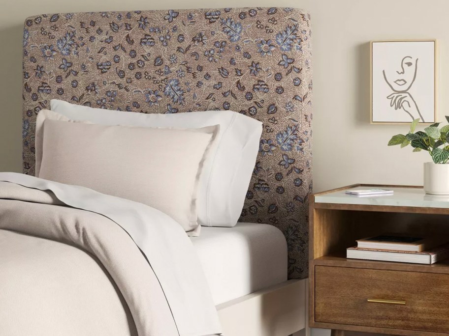 floral headboard with white bedding on bed next to table