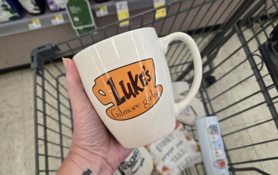 a womans hand holding a ceramic coffee mug