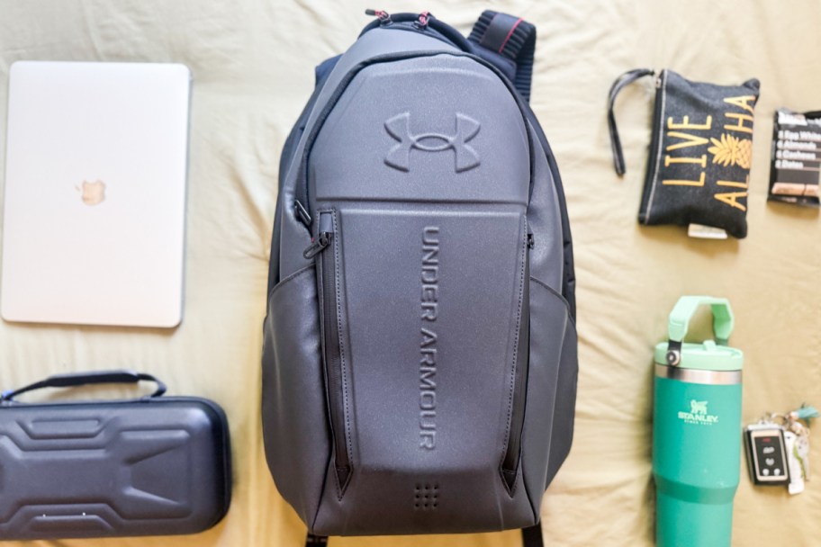 black backpack in the middle of laptop, water bottle, wallet, keys, and more