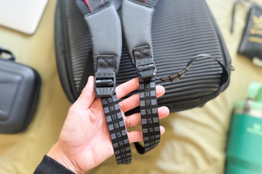 hand holding straps of backpack with numbers on them