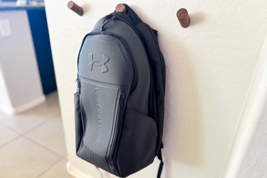 black backpack hanging on wooden hook