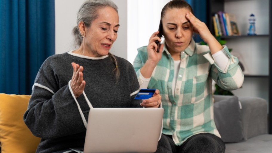 Too concerned, women sitting with laptop and credit card on phone