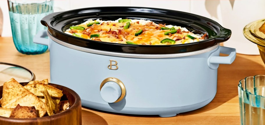shallow light blue slow cooker with cheese dip inside