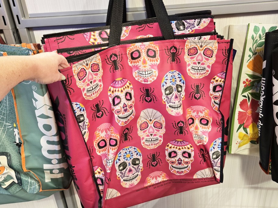 hand grabbing a pink skull print reusable shopping tote