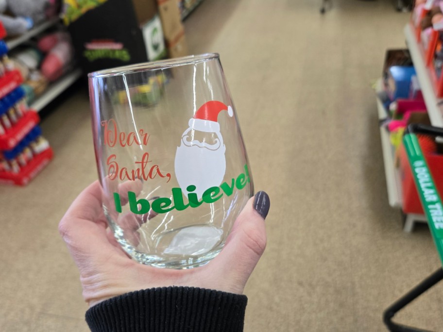 A hand holding up a Christmas glass at Dollar Tree.