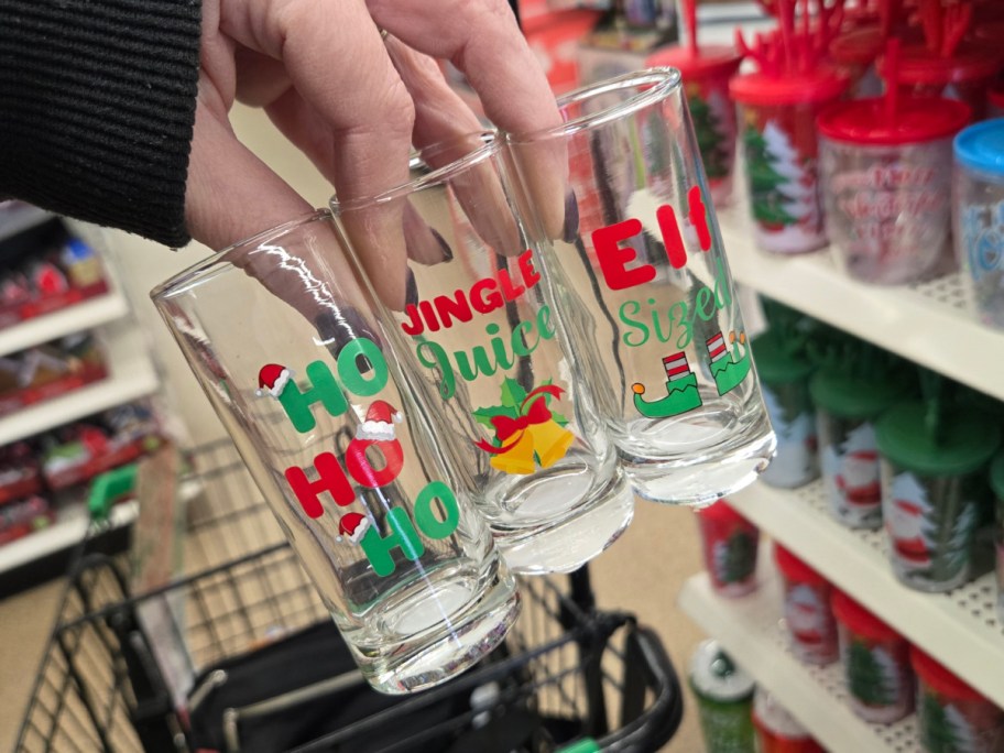 A hand holding Christmas shot glasses at Dollar Tree.