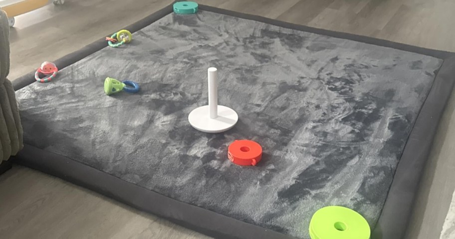 a grey velvet bay play mat with toys on it