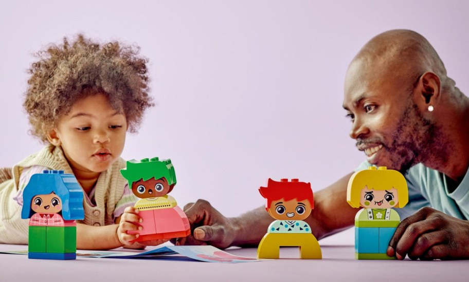 A kid and a man playing with a LEGO DUPLO emotions set.
