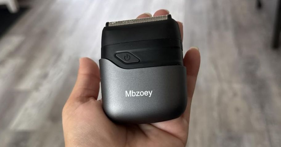 Hand holding a mini electric shaver