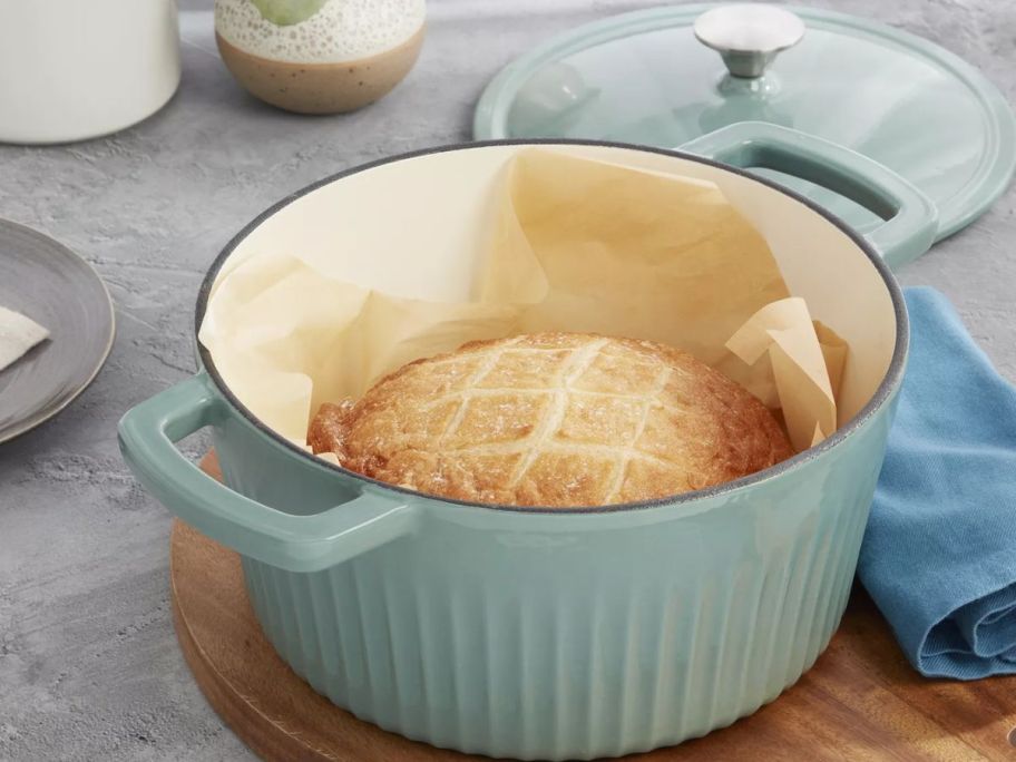 A Mingle & Co. 5qt Fluted Enameled Cast Iron Dutch Oven with a loaf of sourdough inside