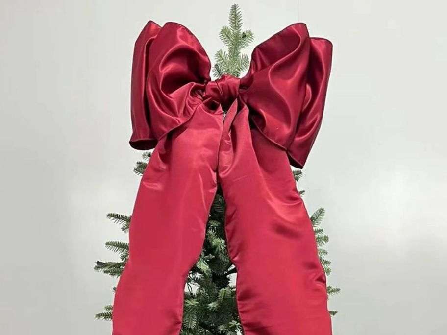 a large red bow at the top of a tree