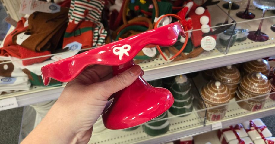 A person holding a red, ceramic cake stand 