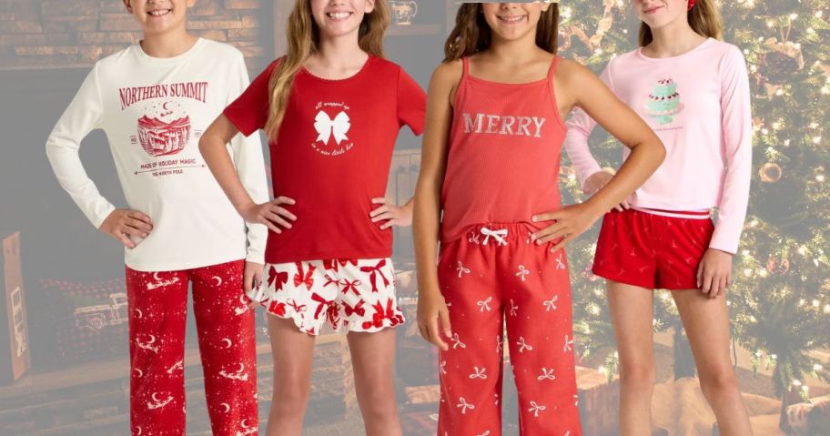 Several kids wearing red and white Christmas outfits in front of a Christmas tree