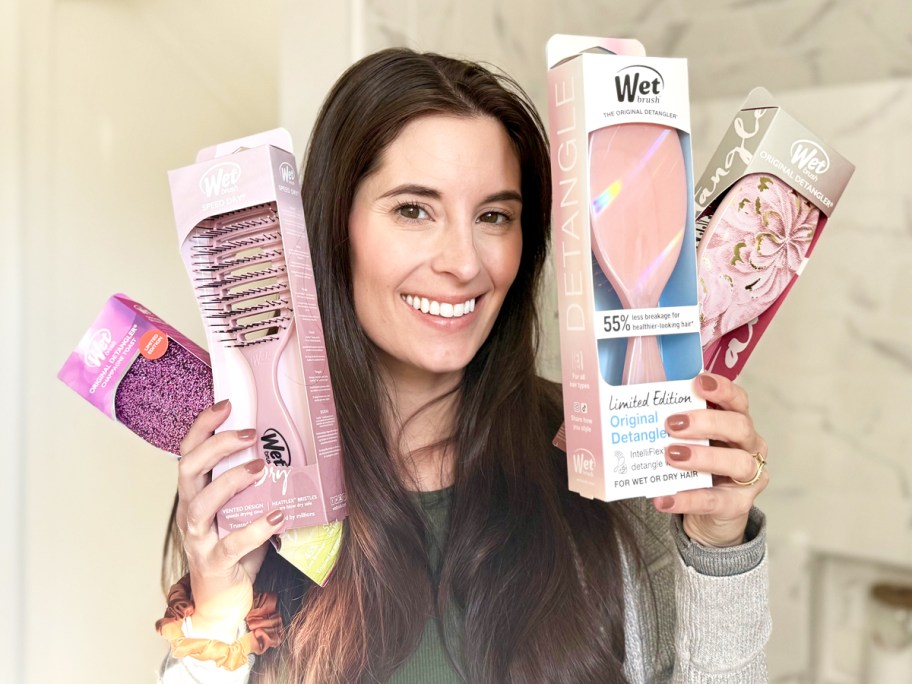 woman holding up 4 pink wet brushes